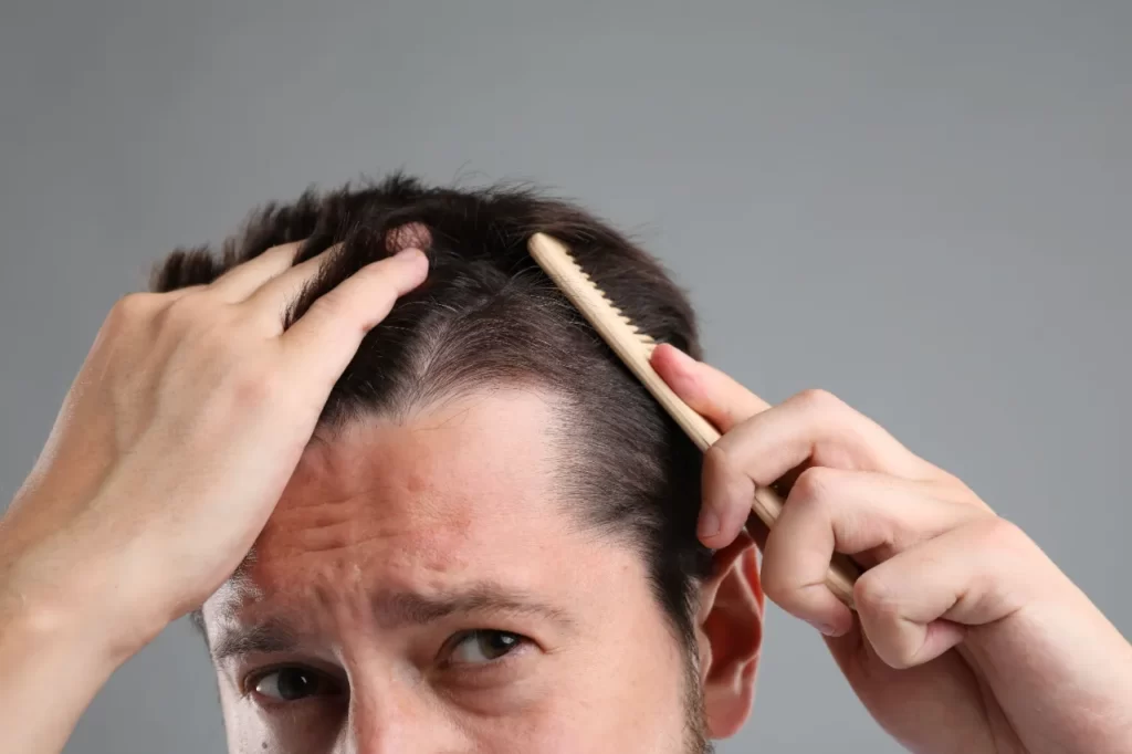 man brushing his hair on gray background closeup utc